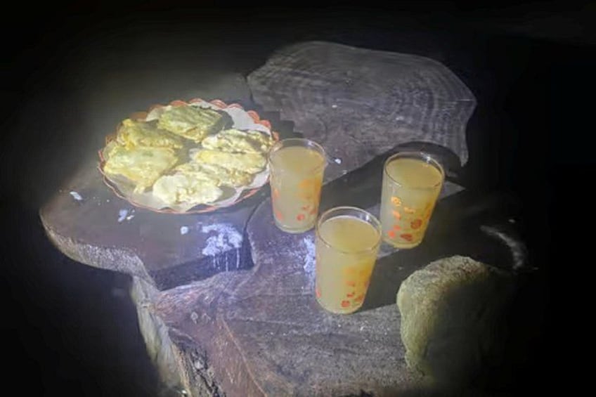 A pie on a wooden surface with three glasses of a yellowish liquid, possibly juice or cider, and a piece of bread. 2