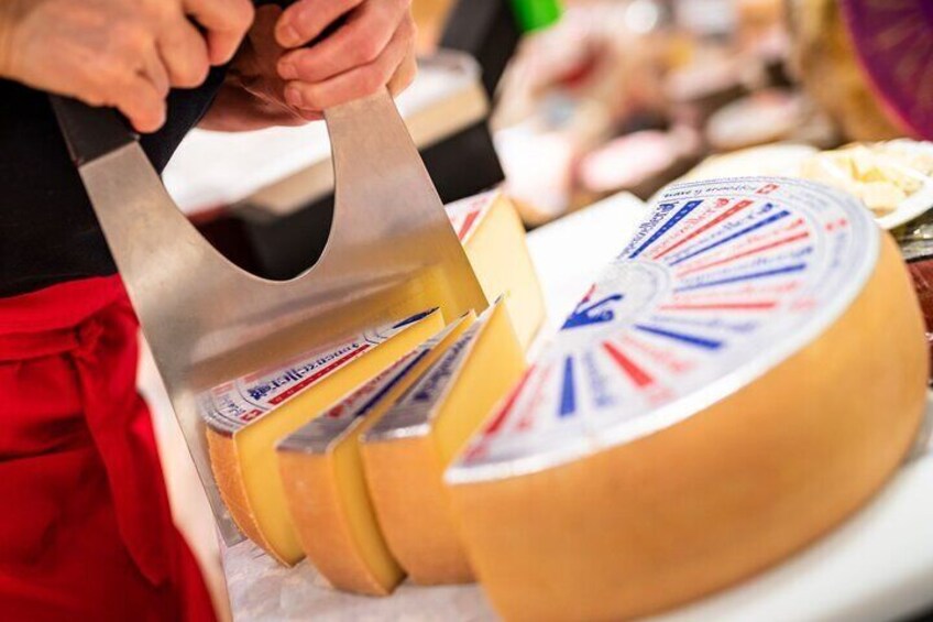 Una persona cortando una rueda de queso con un cuchillo grande. 1