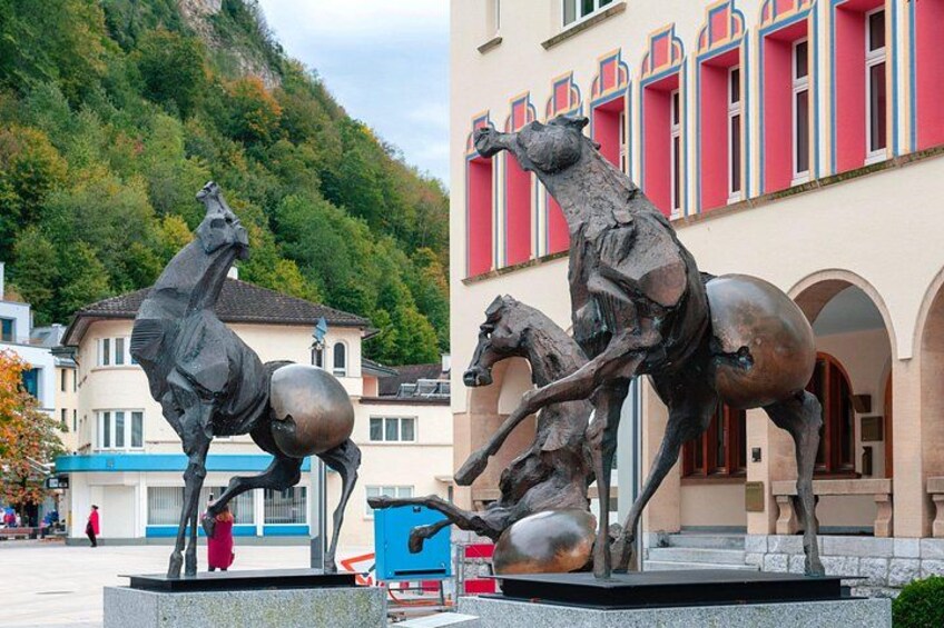 A bronze horse statue in a public square with a building in the background. 4
