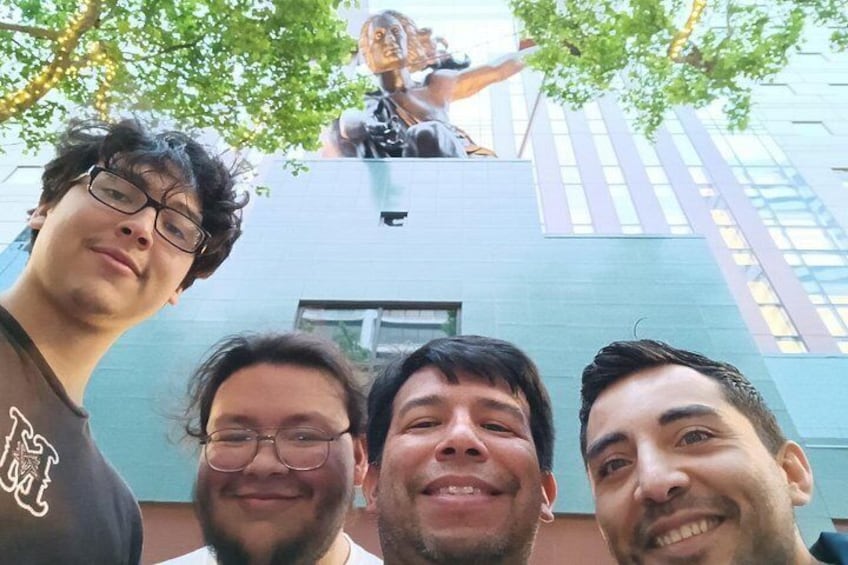 Tre persone in piedi di fronte a un edificio con una statua sulla sommità. 1