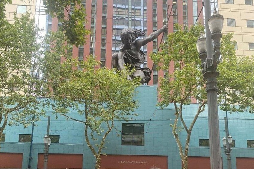 Una statua raffigura una donna che sorregge una torcia, un lampione e un edificio con facciata blu. 5