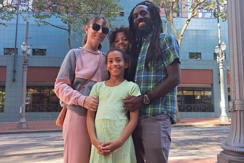 Una famiglia di quattro persone in un ambiente urbano, con edifici e un lampione. 4