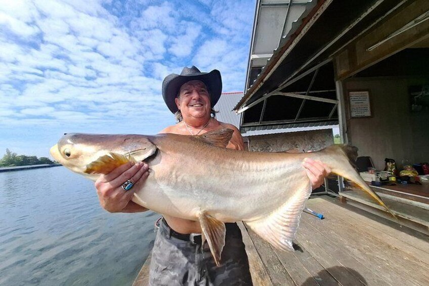A person holding a large fish on a dock. 1