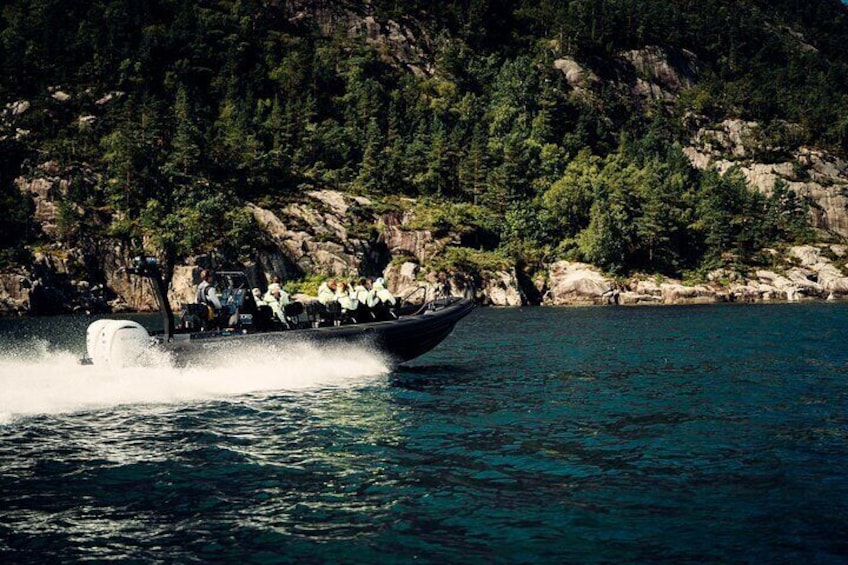 Un bote avanza a toda velocidad por aguas claras, con una costa rocosa y boscosa al fondo. 5