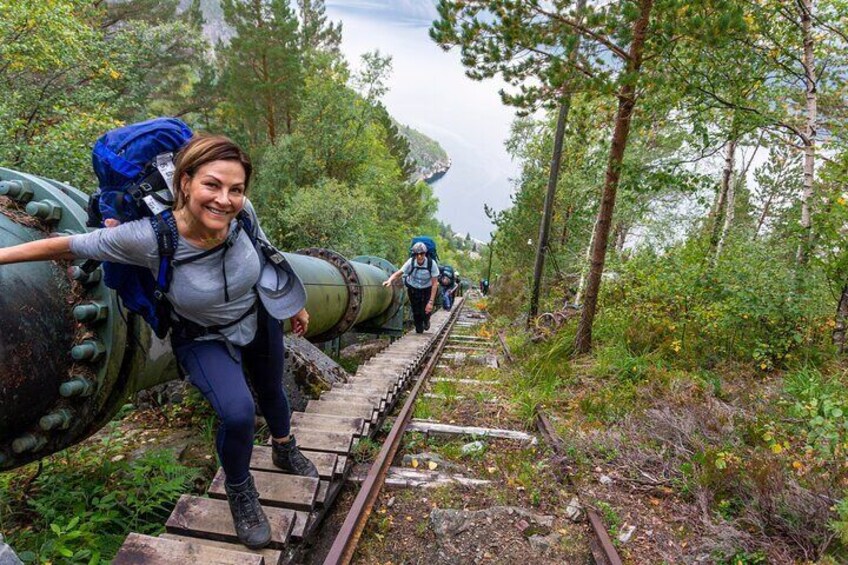 Una persona sube una escalera de madera junto a un tanque verde grande. 1