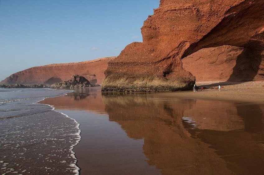 A beach with red rock formations and calm water. 2