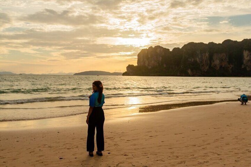 A person standing on a beach facing the ocean with cliffs in the background. 4