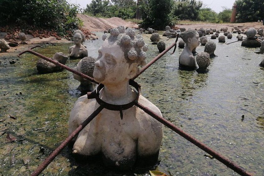 A sculpture garden with multiple statues in a shallow water body, surrounded by greenery. 1