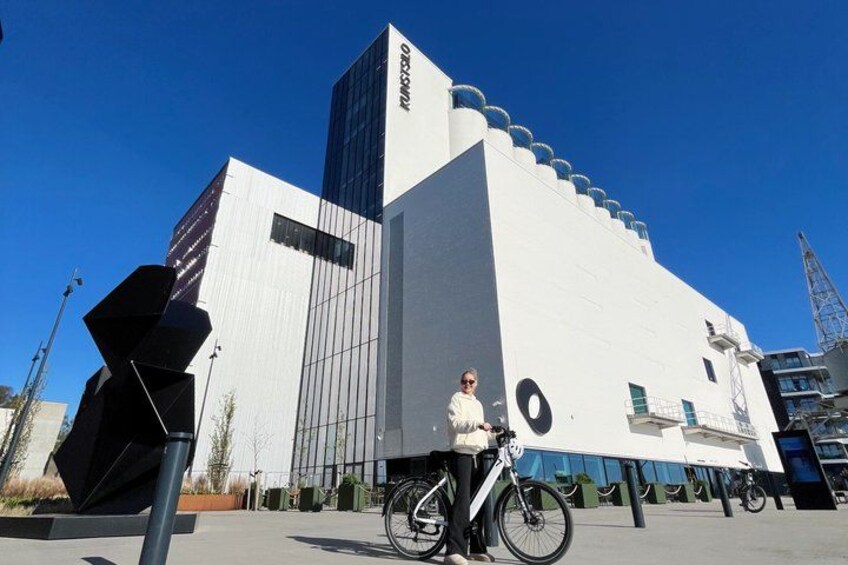 A modern building with a white facade and a large circular window, a bicycle parked in front, and a clear blue sky. 4