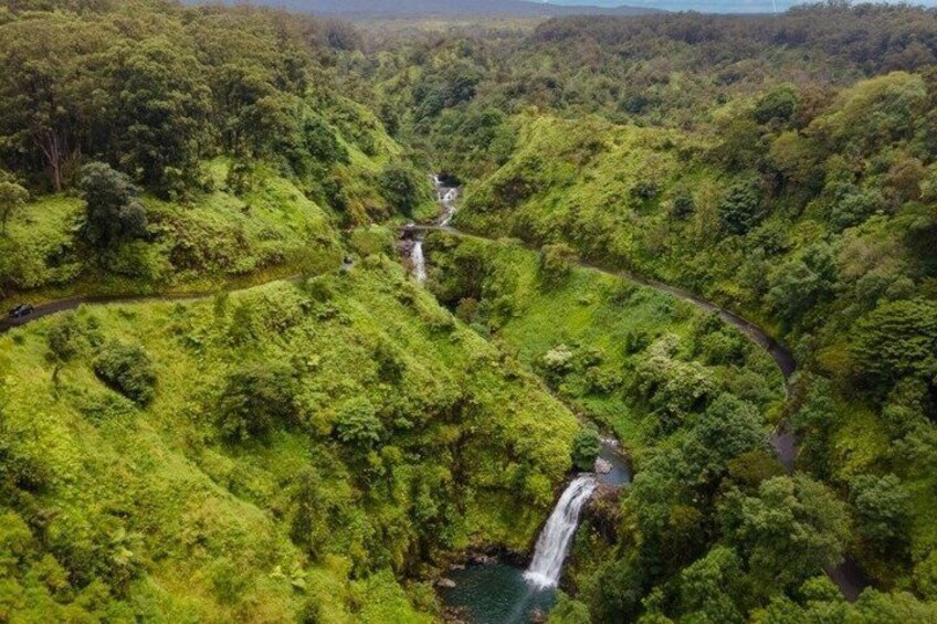Una vallata verdeggiante con una strada tortuosa e una cascata. 2