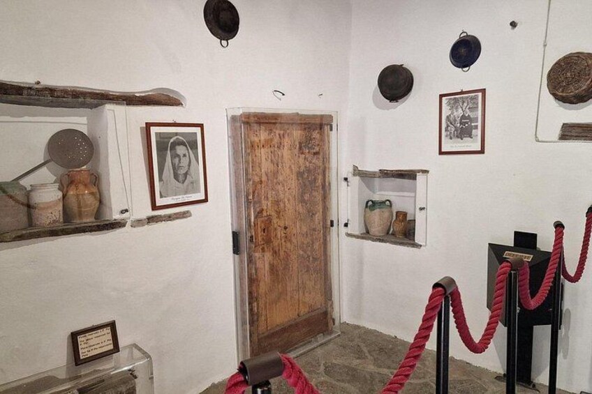 A room with a wooden door, framed pictures, and shelves with pottery. 5