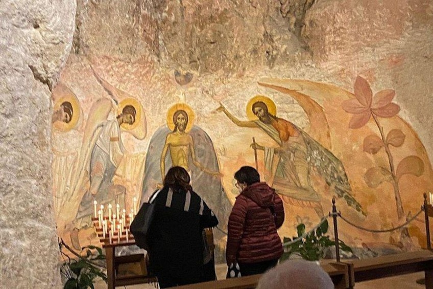 A mural with religious figures and a person praying. 2