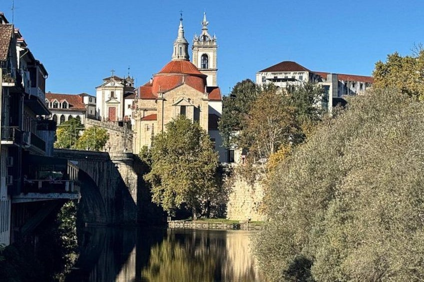 A river with a bridge, a church with a red dome, and buildings along the riverbank. 4
