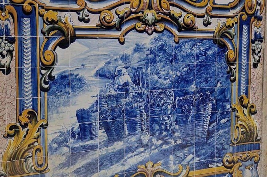 A blue and white tiled wall with a decorative frame and a pastoral scene. 2