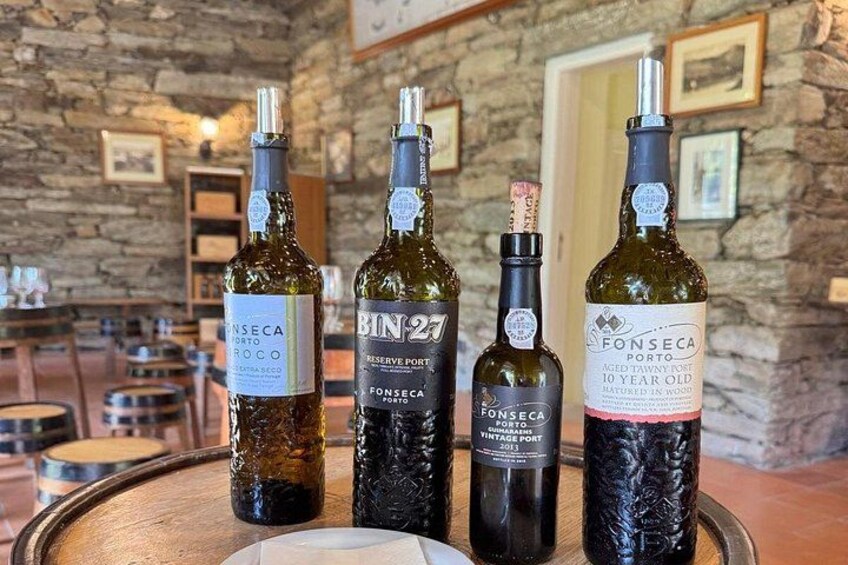 Four bottles of wine on a wooden tray in a rustic setting with stone walls and wooden furniture. 3