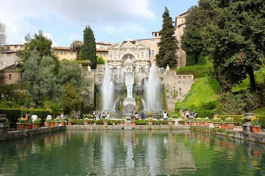 A historic fountain, a large body of water, and surrounding greenery. 1
