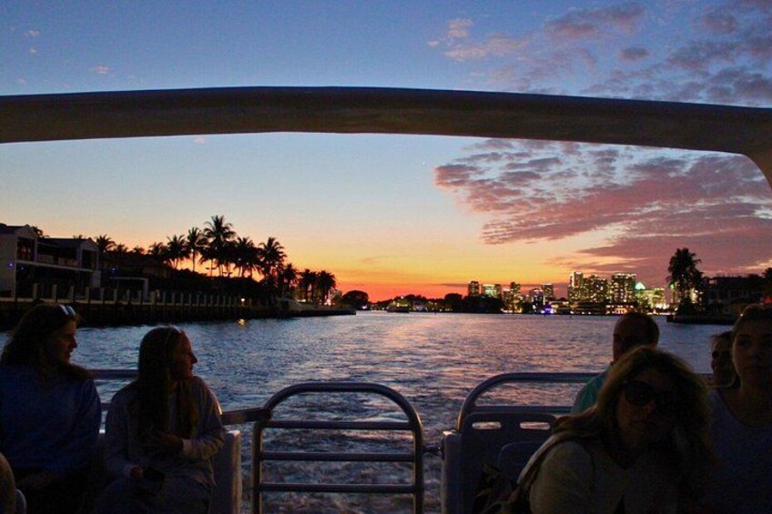 A sunset over a body of water with buildings and palm trees in the background. 3