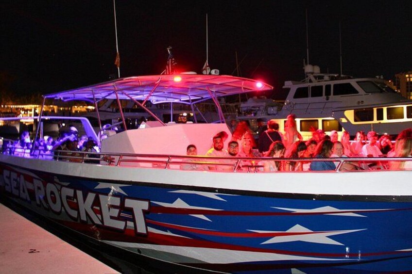 A boat named 'Sea Rocket' with people on board, docked at a marina with other boats in the background. 5