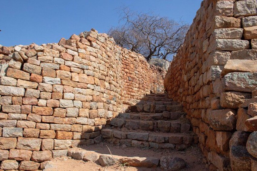 Una escalera de piedra que sube una colina, rodeada de muros de piedra. 3