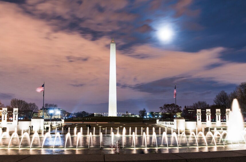 The Washington Monument with a fountain in the foreground and a full moon in the background. 3