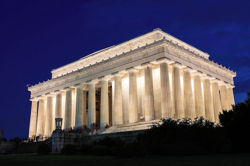 A large neoclassical building with a prominent portico and columns, illuminated at night. 2