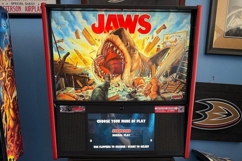 A vintage arcade game titled 'JAWS' with a shark attacking a cityscape. 4