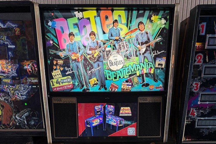 A jukebox with The Beatles album cover and multiple coin slots. 3
