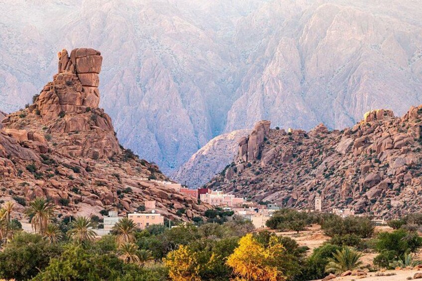 Un cañón rocoso con una formación rocosa destacada y un pequeño asentamiento con edificios. 5