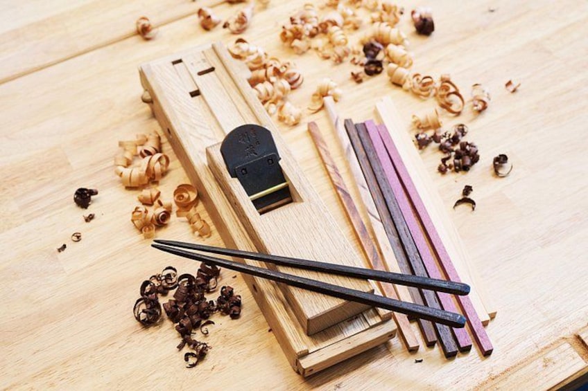 Un outil de travail du bois, avec des copeaux de bois, un ciseau et un bloc de bois, posés sur une table. 1