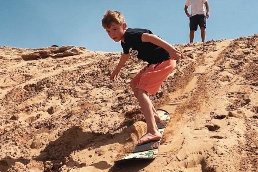 A person riding a skateboard down a sandy slope. 5