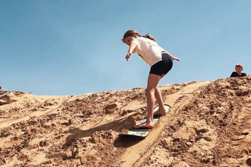 A person riding a snowboard down a sandy slope. 2