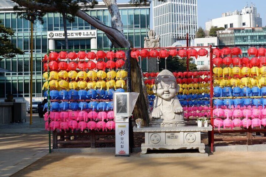 Une statue d’enfant se trouve devant une composition colorée de lanternes rouges, jaunes, bleues et roses. 3