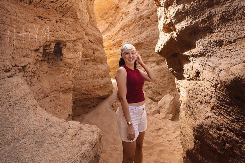 A person standing in a narrow canyon with rocky walls. 4