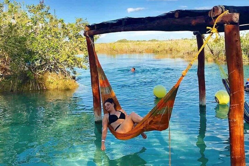 Una persona descansando en una hamaca sobre el agua, rodeada de paisaje natural. 3