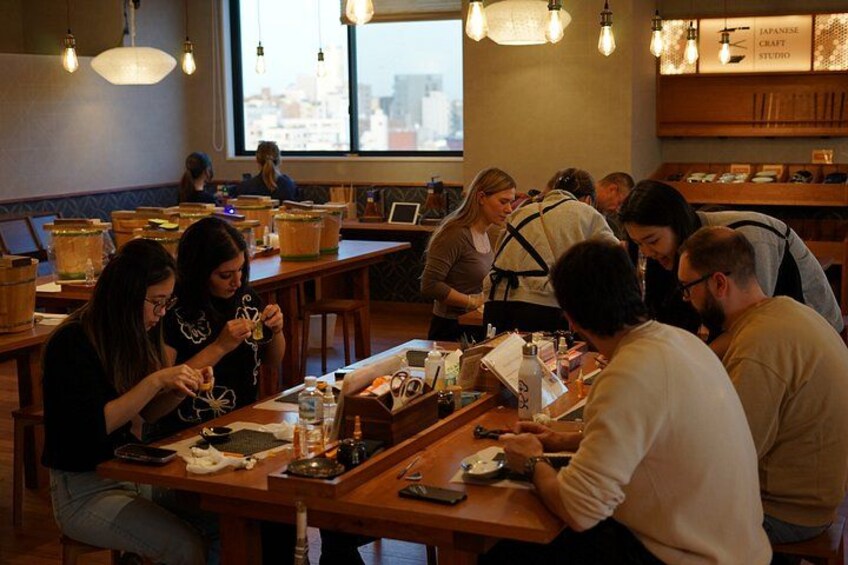 A group of people sitting at tables in a cafe with wooden furniture and hanging light fixtures. 2