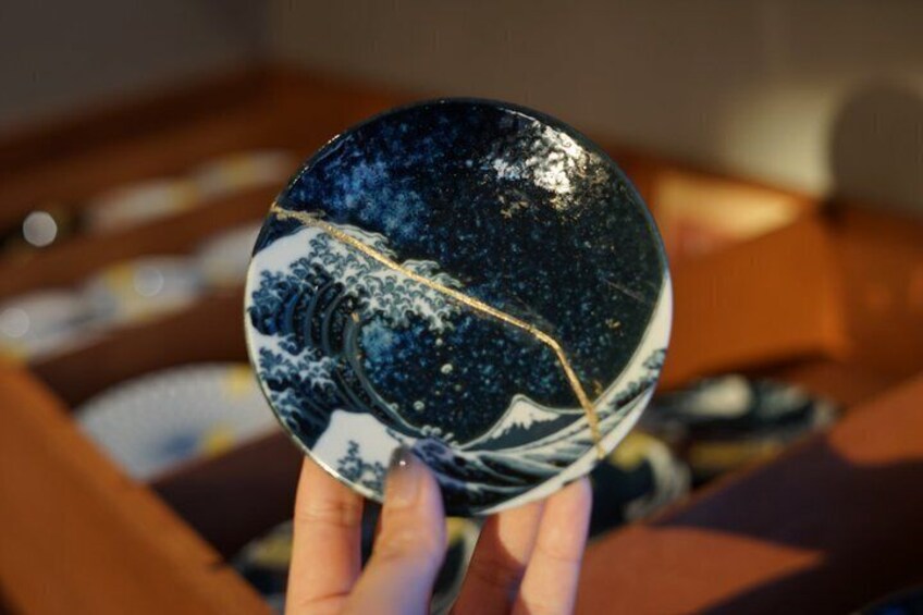 A hand holding a round ceramic plate with a blue and white design. 1