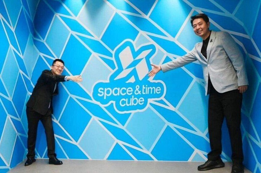 To personer foran en blå væg med et geometrisk mønster og teksten 'space & time cube'. 1