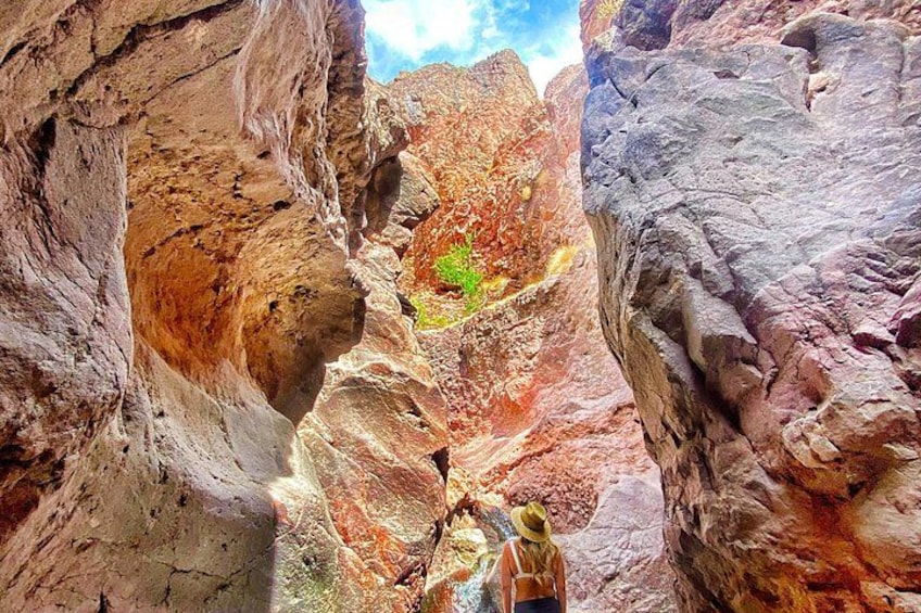 A canyon with red and brown rock formations, a person wearing a hat and carrying a backpack. 3