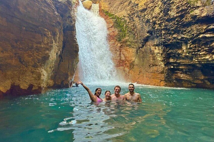 A waterfall, clear water, and people swimming. 3