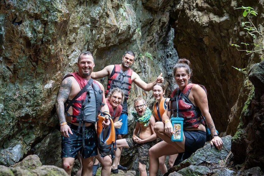 A group of people in a rocky outdoor setting, wearing life jackets and climbing gear. 2
