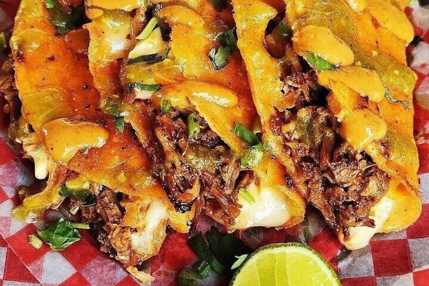 A close-up of a dish with shredded meat, melted cheese, and green herbs, possibly a type of taco or burrito. 5