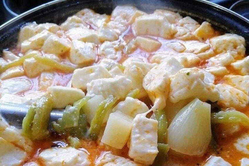 A pan with tofu and vegetables in a simmering sauce. 4