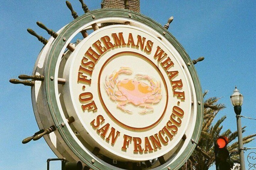 A circular sign with a fish emblem and text reading 'FISHERMANS WHARF OF SAN FRANCISCO'. 4