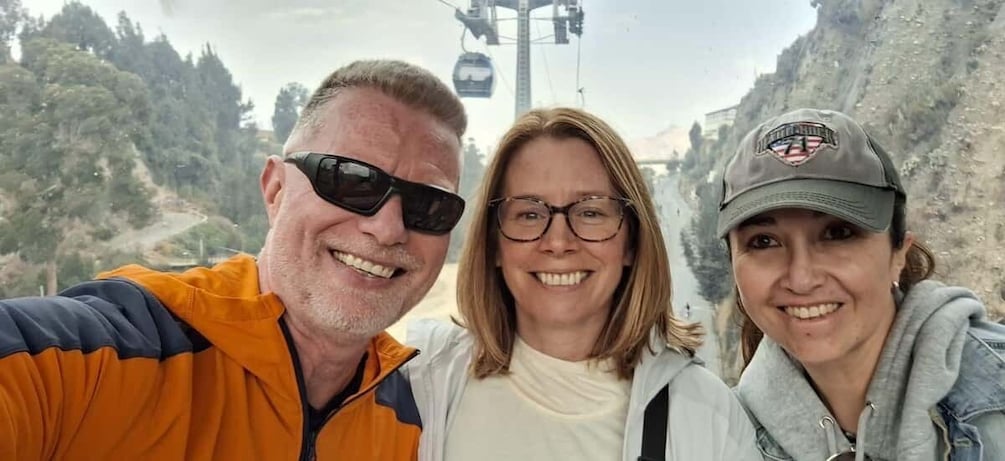 Three people in a mountainous area with a ski lift in the background. 1