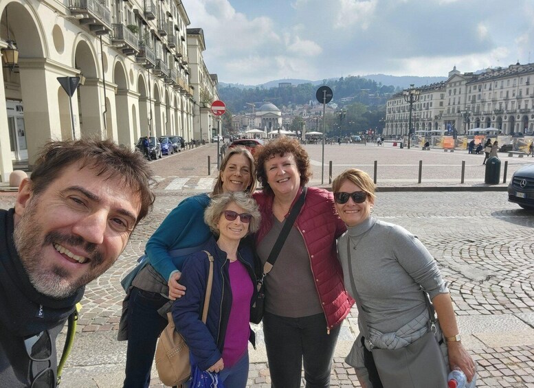 A group of people posing in a city square with historic buildings and a clear sky. 4