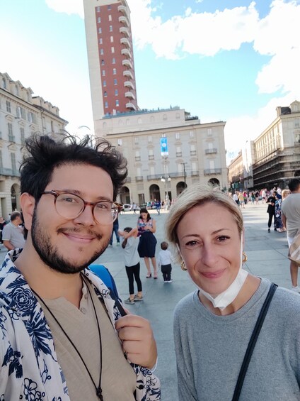 A man and a woman standing in a public square with historic buildings in the background. 3