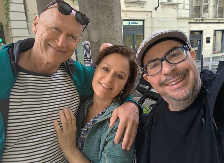 Three people posing together outdoors with a building in the background. 1