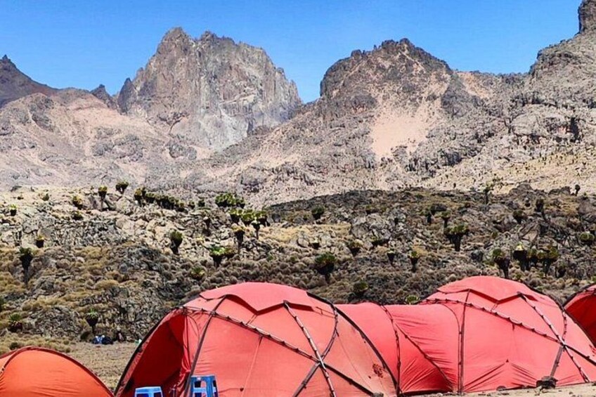 Red tents set up in a mountainous area with rocky terrain and sparse vegetation. 2