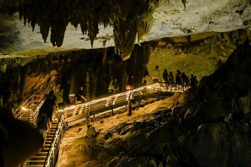 A cave with a staircase leading to a higher level, surrounded by rock formations and dim lighting. 4