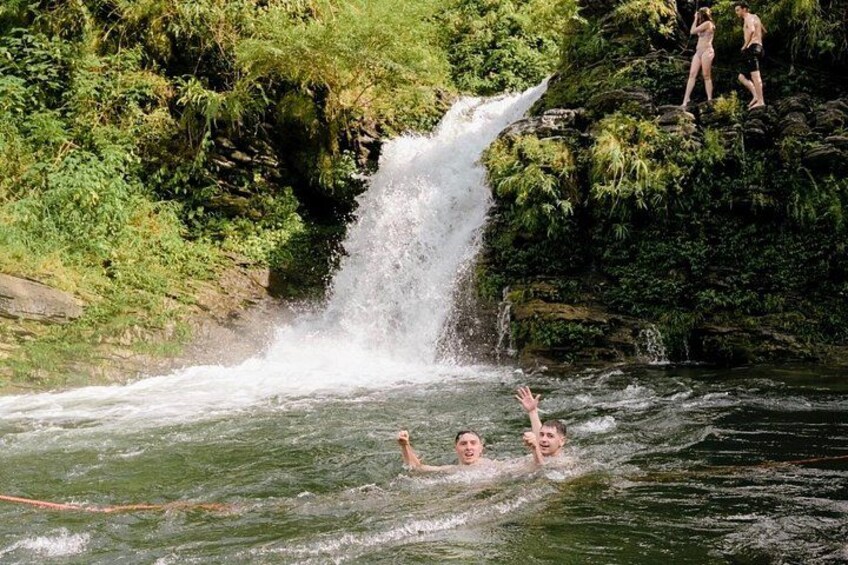 A waterfall, a river, and people swimming and standing on rocks. 5